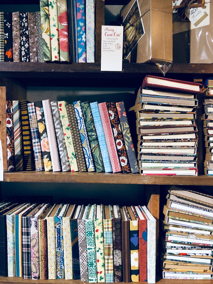 A collection of colorful handcrafted notebooks stacked on wooden shelves in Hue, Vietnam.